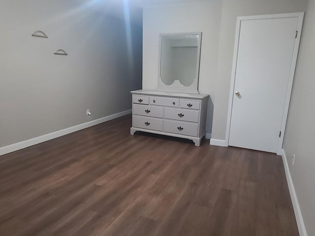 unfurnished bedroom with baseboards and dark wood finished floors