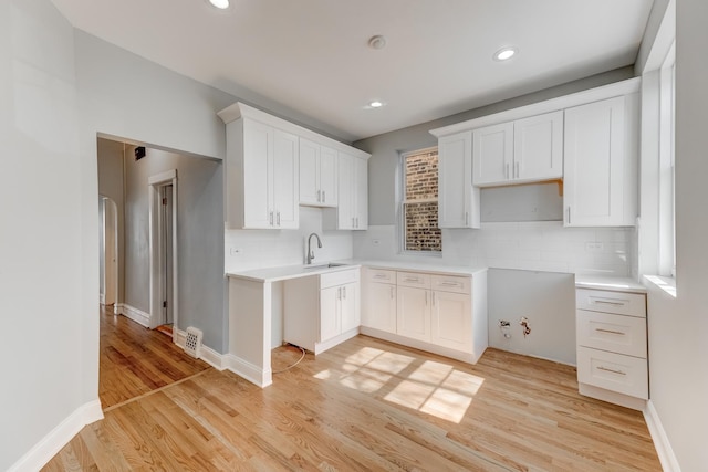 kitchen featuring recessed lighting, a sink, light wood-type flooring, decorative backsplash, and white cabinetry