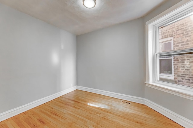 unfurnished room featuring baseboards, visible vents, and wood-type flooring