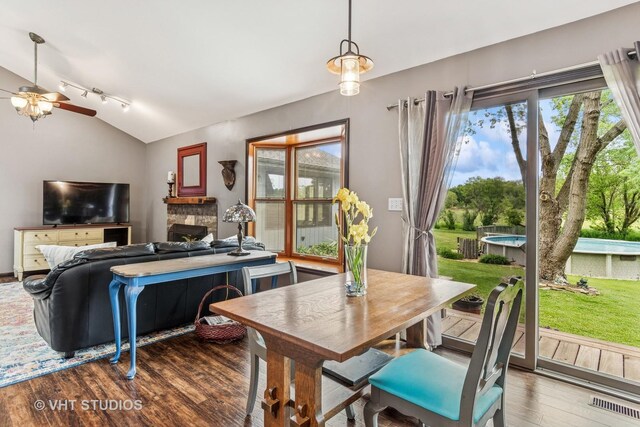 62 Foxhurst Ln, Newark, IL 60541 - dining area featuring vaulted ceiling, wood finished floors, a ceiling fan, a fireplace, and track lighting