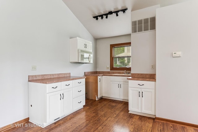 62 Foxhurst Ln, Newark, IL 60541 - kitchen with track lighting, white microwave, vaulted ceiling, wood finished floors, and white cabinetry