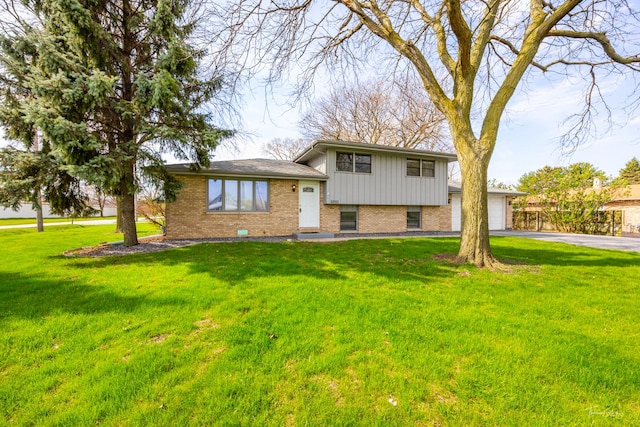 tri-level home with a front lawn, brick siding, board and batten siding, aphalt driveway, and an attached garage