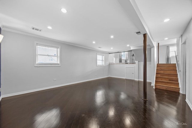 unfurnished living room featuring baseboards, visible vents, dark wood finished floors, and crown molding