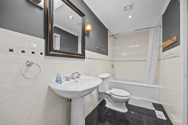 full bath with wainscoting, tile walls, shower / bathtub combination with curtain, toilet, and visible vents