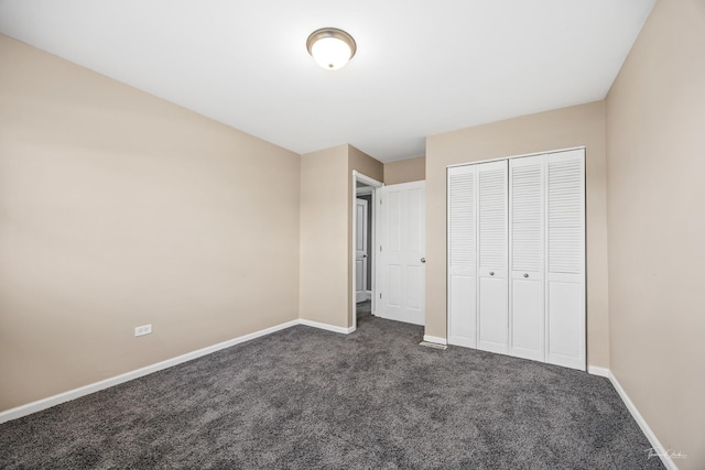 unfurnished bedroom featuring a closet, dark carpet, and baseboards