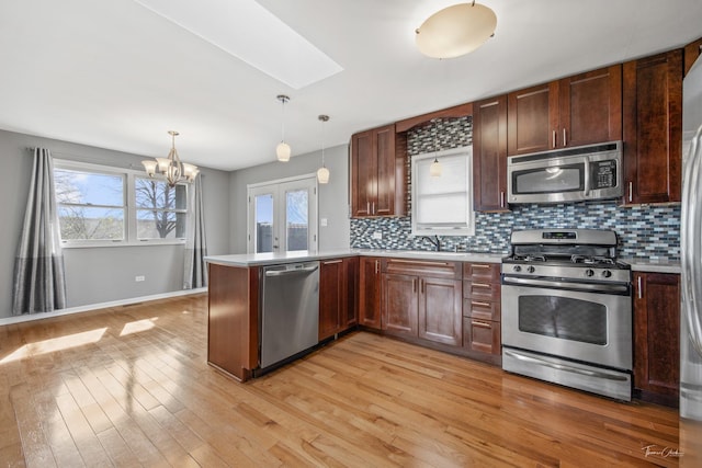 kitchen featuring a skylight, backsplash, appliances with stainless steel finishes, and light countertops