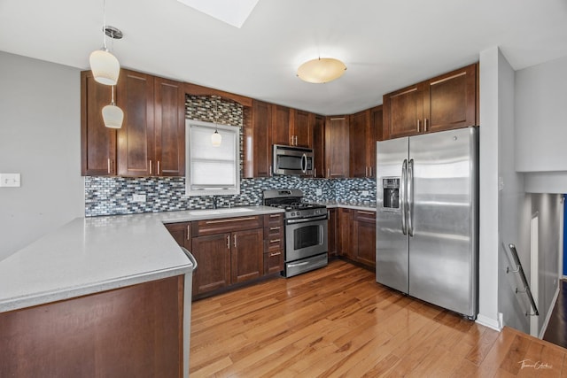 kitchen featuring light wood-type flooring, tasteful backsplash, stainless steel appliances, and light countertops