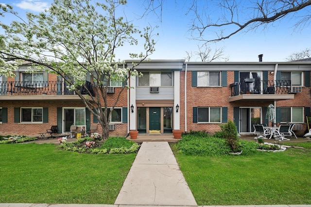 exterior space featuring brick siding, a balcony, a yard, and a patio area