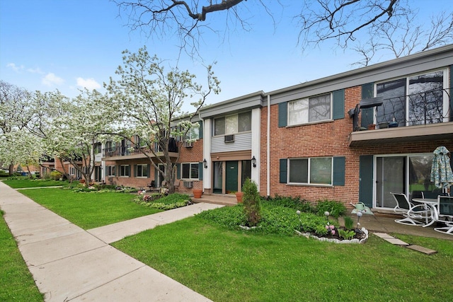 view of front of house with brick siding, a front lawn, and a balcony