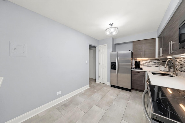 kitchen featuring stainless steel appliances, light countertops, dark brown cabinets, backsplash, and a sink