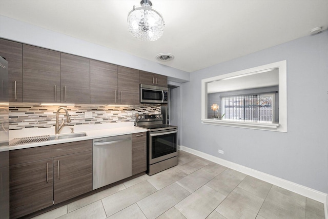 kitchen with a sink, stainless steel appliances, tasteful backsplash, visible vents, and light countertops