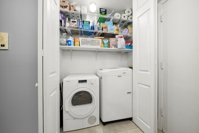 clothes washing area featuring light tile patterned flooring, separate washer and dryer, and laundry area