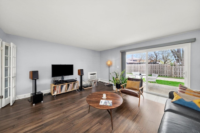 living area featuring a baseboard heating unit, wood finished floors, and baseboards