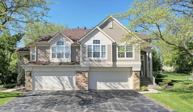 view of front of house featuring driveway, stone siding, and an attached garage