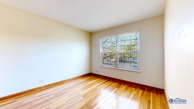 spare room with baseboards and light wood-style floors