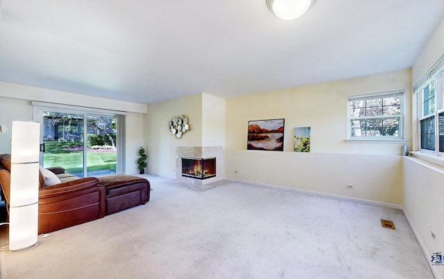 carpeted living room with a multi sided fireplace and baseboards