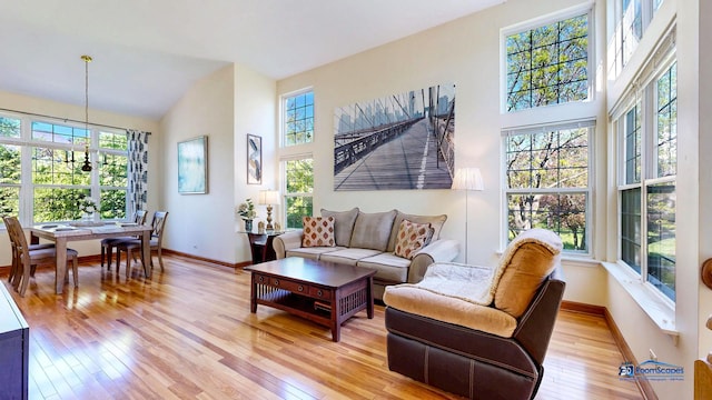 living area featuring healthy amount of natural light, light wood-style flooring, and high vaulted ceiling