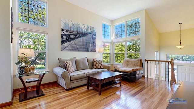 living area featuring a high ceiling, light wood-type flooring, and baseboards