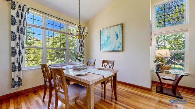 dining area with a chandelier, light wood-style flooring, plenty of natural light, baseboards, and high vaulted ceiling