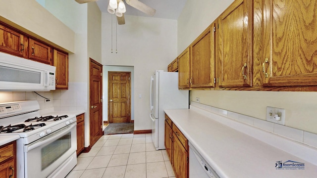kitchen with white appliances, brown cabinetry, light countertops, a towering ceiling, and ceiling fan