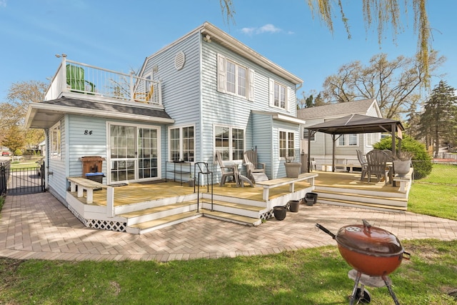 rear view of house with a deck, fence, a gazebo, a patio area, and a balcony