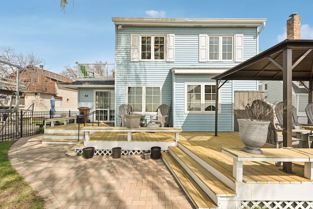 rear view of house featuring a wooden deck and fence