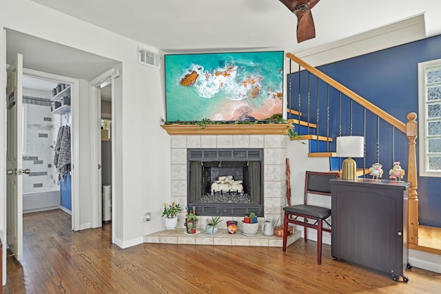 living room featuring visible vents, baseboards, wood finished floors, and a fireplace
