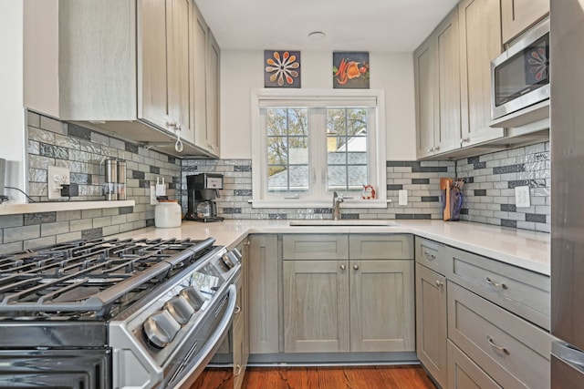 kitchen featuring appliances with stainless steel finishes, light countertops, gray cabinets, and a sink