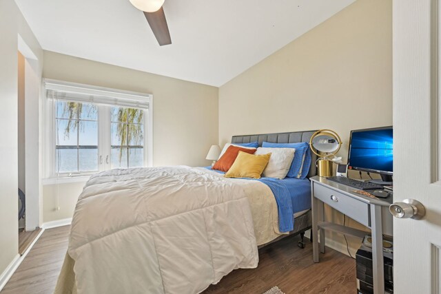 bedroom with wood finished floors, a ceiling fan, vaulted ceiling, and baseboards