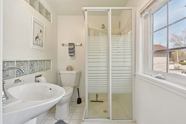 bathroom with tile patterned flooring, a shower stall, toilet, a sink, and baseboards
