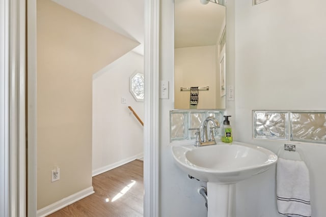 bathroom with baseboards, wood finished floors, and a sink
