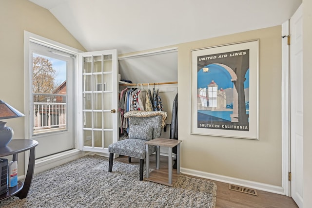 sitting room featuring baseboards, visible vents, wood finished floors, and vaulted ceiling