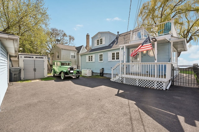 colonial inspired home with a storage shed, a chimney, a balcony, and an outbuilding