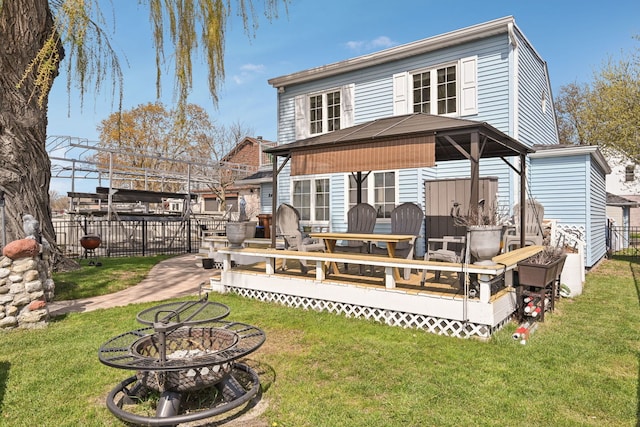 rear view of house featuring fence, a wooden deck, a gazebo, and a yard