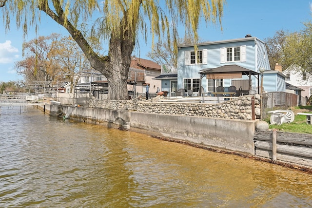 rear view of property with a patio, a gazebo, and a water view