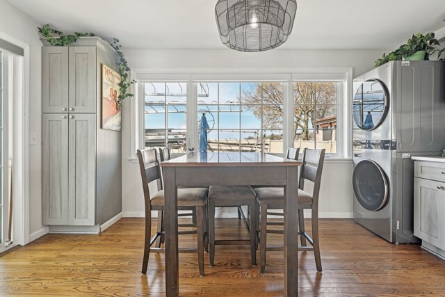 dining area with baseboards, stacked washing maching and dryer, and light wood-type flooring