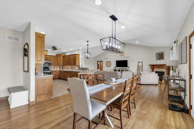 dining room featuring visible vents, recessed lighting, light wood-style floors, lofted ceiling, and a fireplace