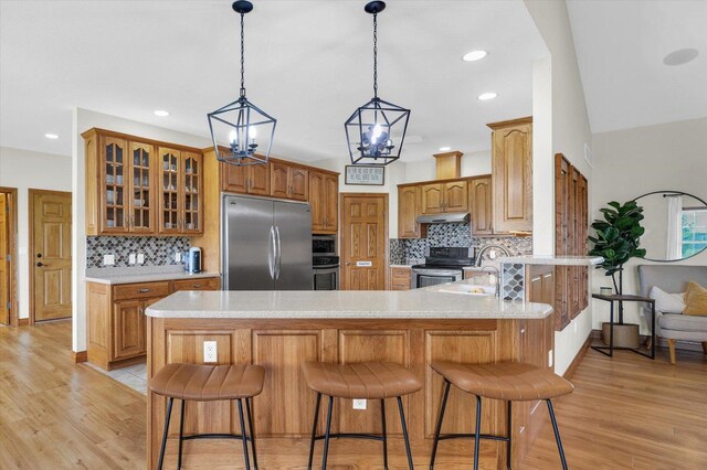 kitchen with a sink, decorative backsplash, appliances with stainless steel finishes, a peninsula, and under cabinet range hood