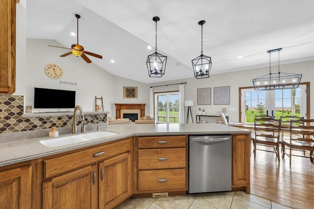 kitchen with stainless steel dishwasher, a sink, brown cabinets, open floor plan, and a fireplace