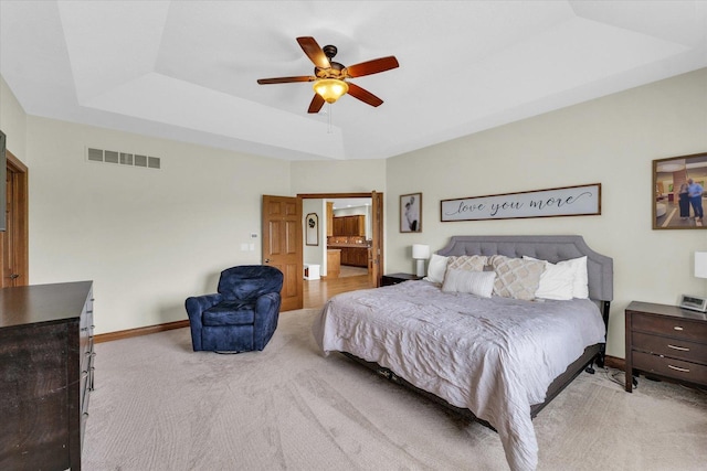 bedroom featuring a raised ceiling, visible vents, light carpet, baseboards, and ceiling fan