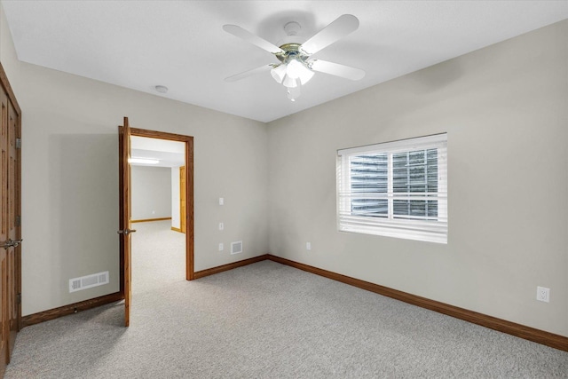unfurnished room featuring baseboards, visible vents, a ceiling fan, and light colored carpet