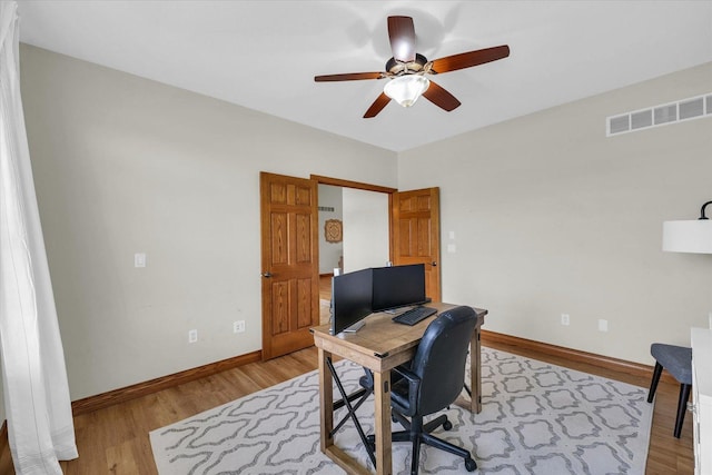 home office with light wood-type flooring, visible vents, baseboards, and ceiling fan