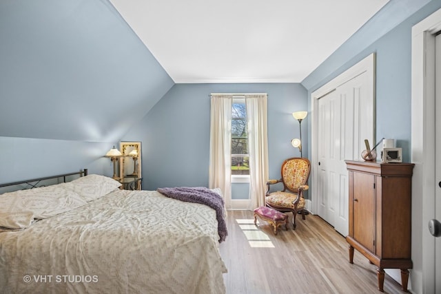 bedroom with light wood-type flooring, a closet, and vaulted ceiling