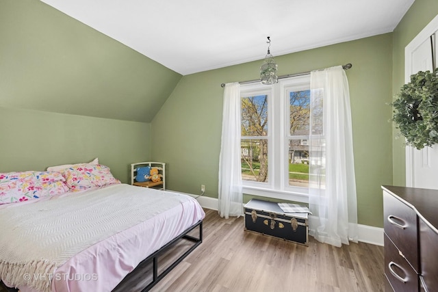 bedroom with baseboards, wood finished floors, and lofted ceiling