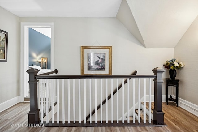 stairway with wood finished floors, vaulted ceiling, and baseboards