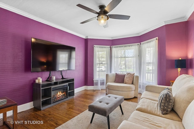 living room with baseboards, wood finished floors, a ceiling fan, and crown molding