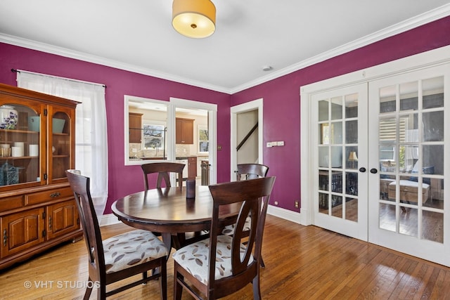 dining room with plenty of natural light, baseboards, light wood-type flooring, french doors, and crown molding