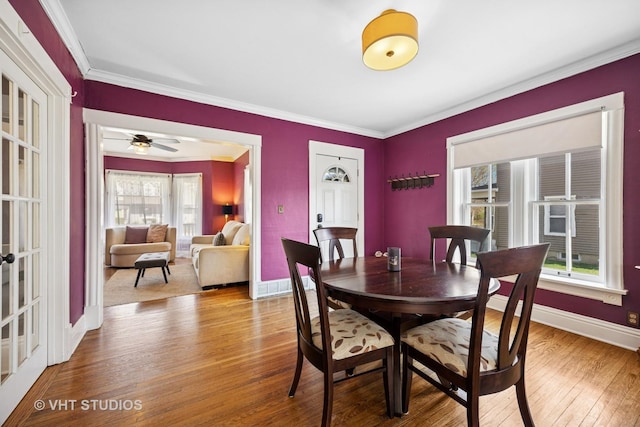 dining area featuring baseboards, wood finished floors, and crown molding
