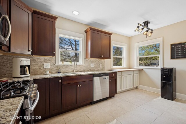 kitchen featuring light tile patterned floors, backsplash, appliances with stainless steel finishes, and a sink