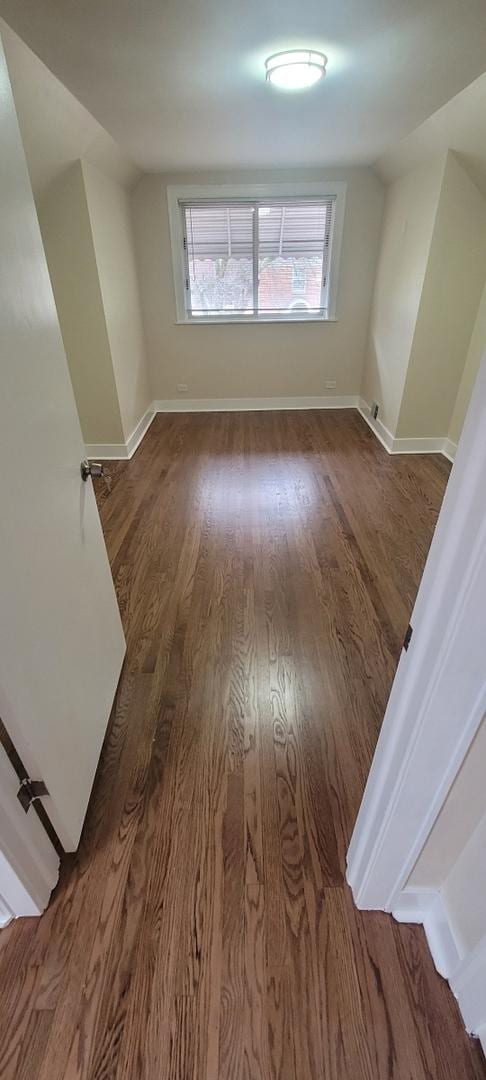 interior space with lofted ceiling, wood finished floors, and baseboards